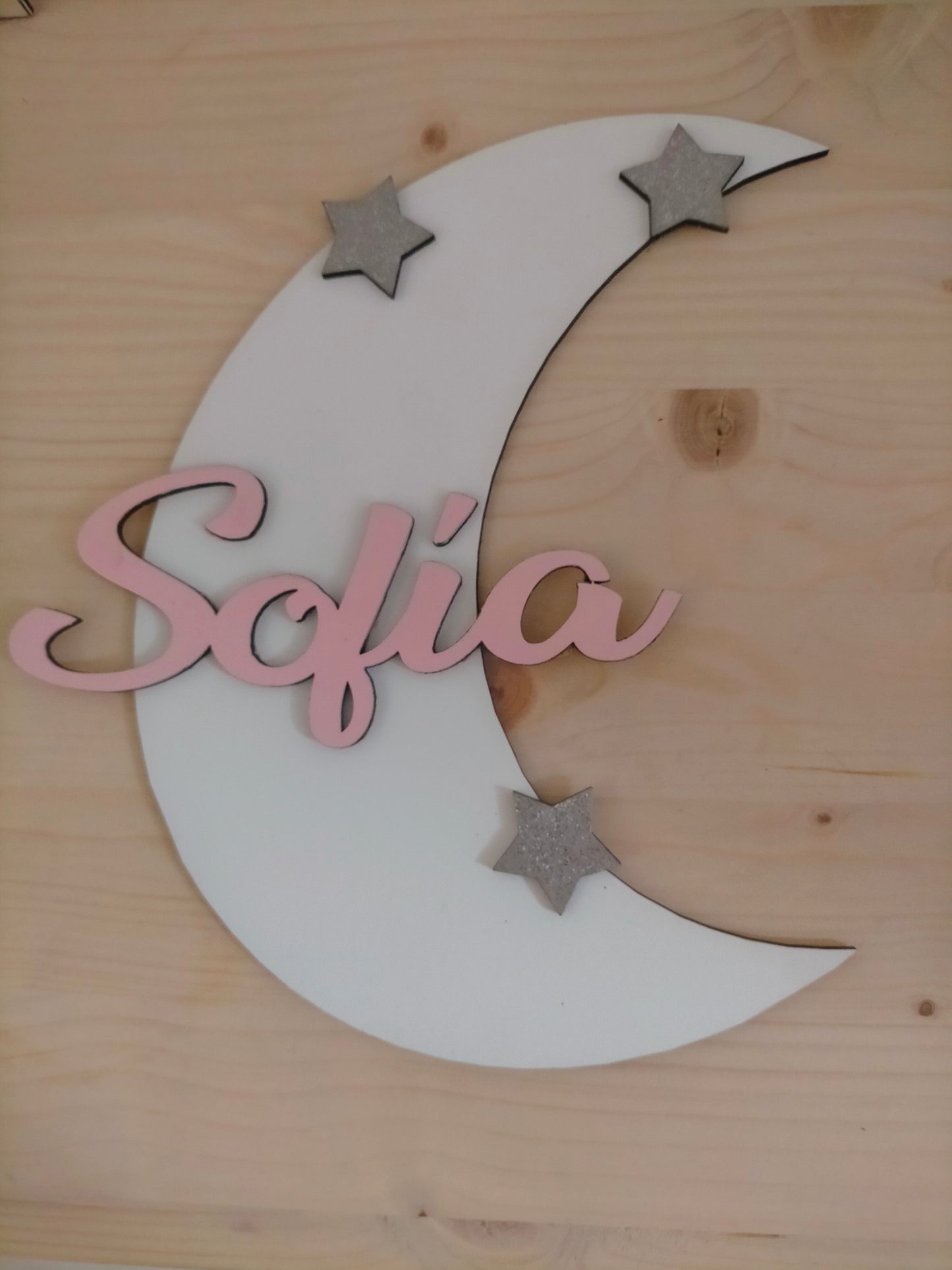 White wooden crescent moon with personalized pink name and silver stars decoration on wooden background