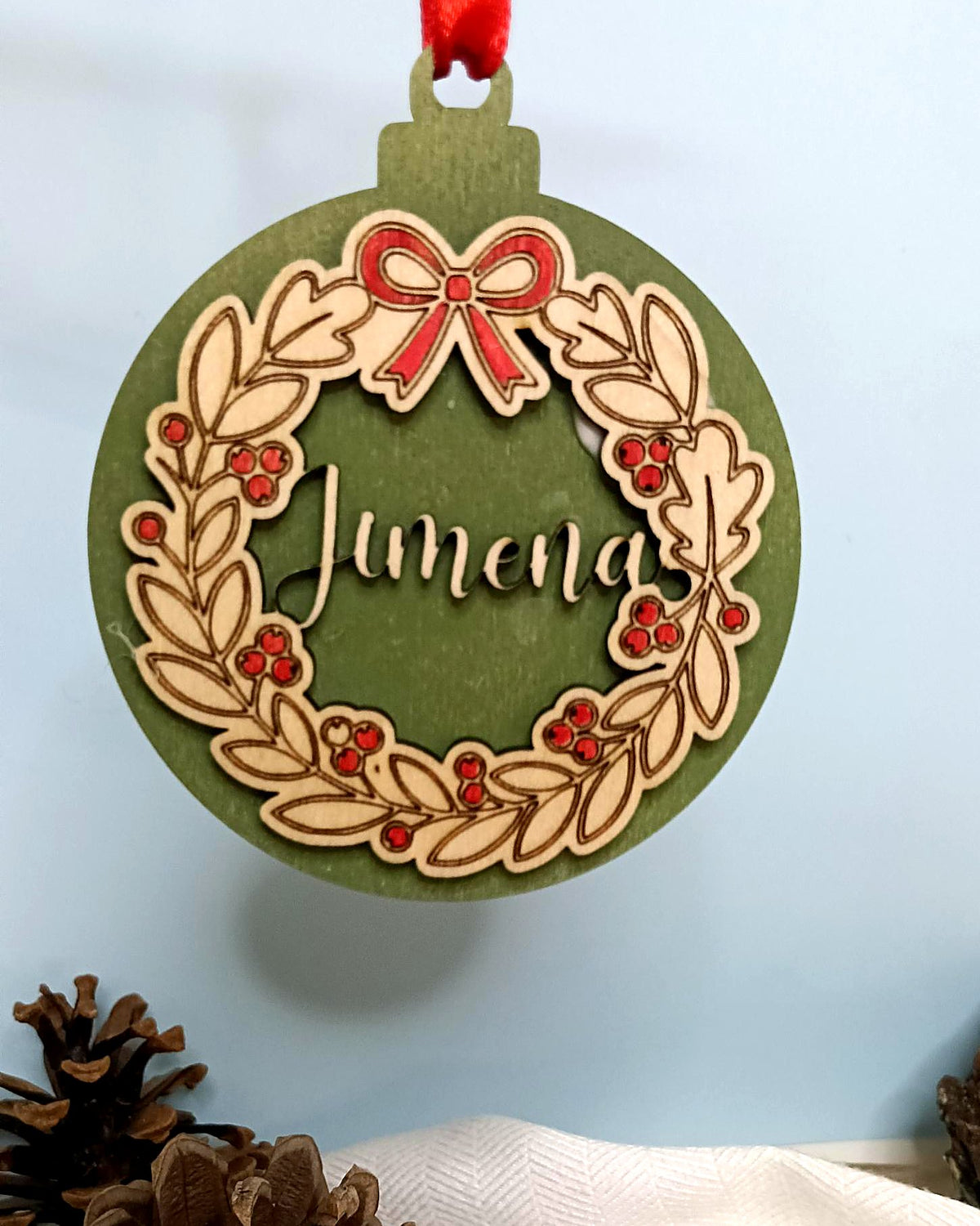 Bola de Navidad verde con corona de hojas y nombre recortado